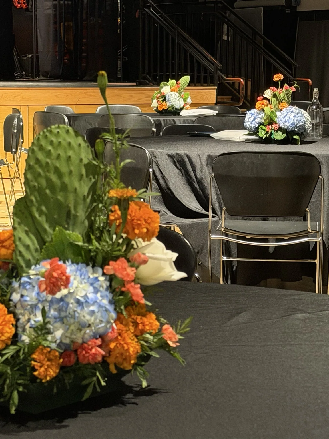 Centerpieces on black-clothed tables in an event hall
