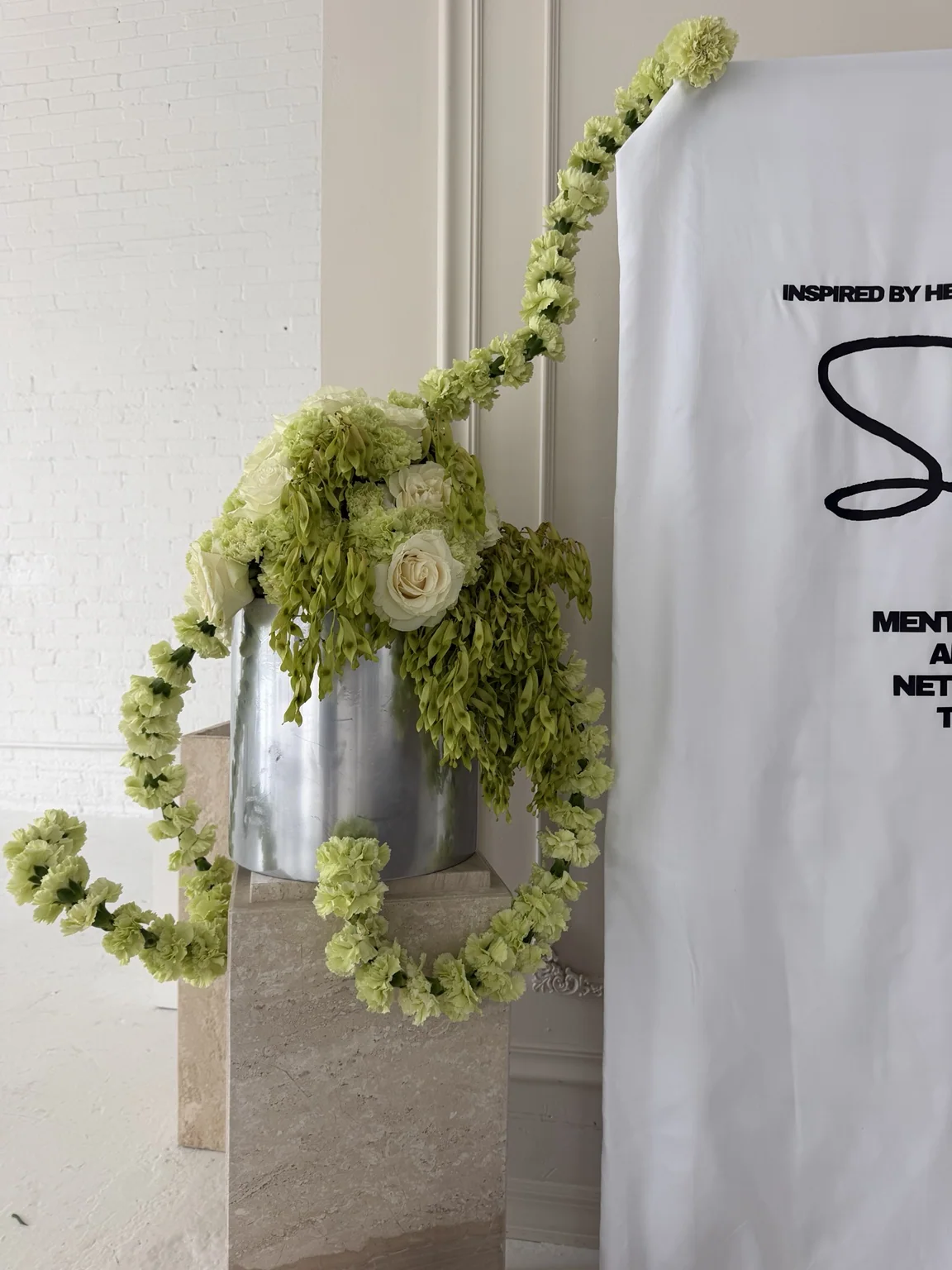 Green carnation and moss installation draped from a hanging white garment