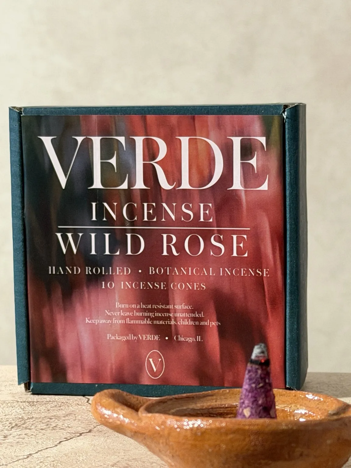 Close view of the VERDE Wild Rose incense packaging with a burning cone in a clay dish
