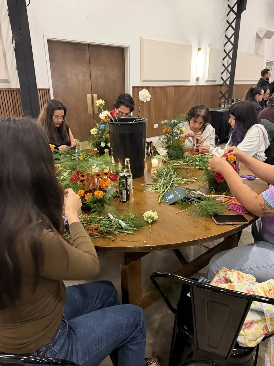Workshop participants arranging marigolds and greenery at a round table