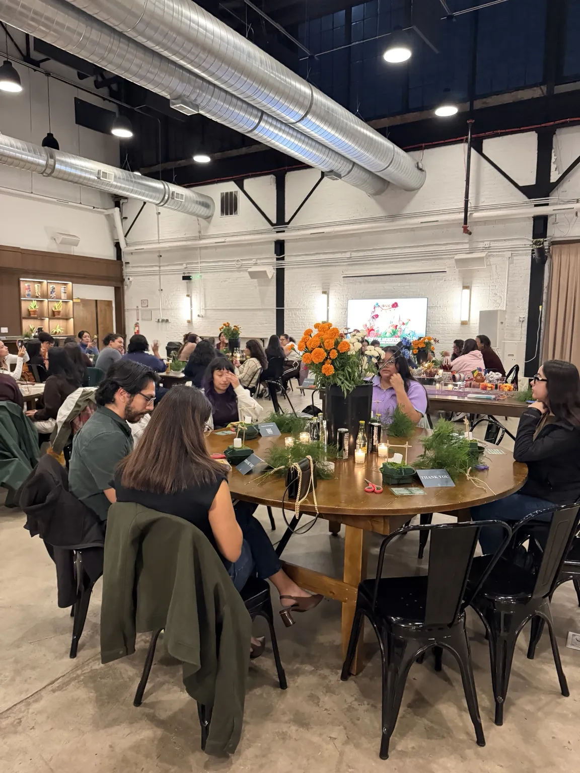 Wide view of the Día de Muertos floral workshop with guests at candlelit tables